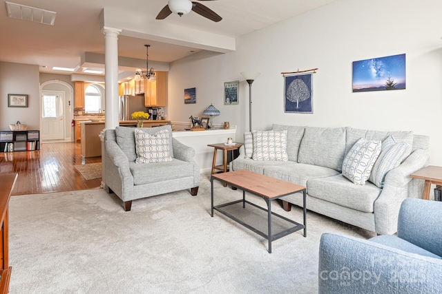 living room with visible vents, light wood-type flooring, a ceiling fan, and light carpet