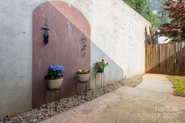 view of side of home featuring stucco siding and fence