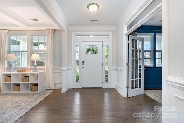 foyer with plenty of natural light, dark wood-type flooring, ornamental molding, a wainscoted wall, and a decorative wall
