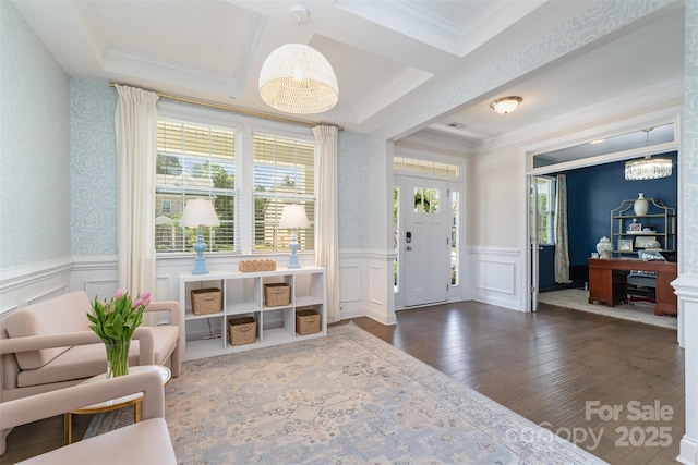 entryway featuring ornamental molding, a wainscoted wall, wood finished floors, a decorative wall, and a chandelier