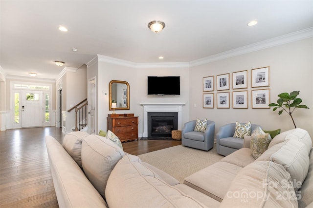 living room featuring ornamental molding, wood finished floors, stairs, a fireplace with flush hearth, and recessed lighting