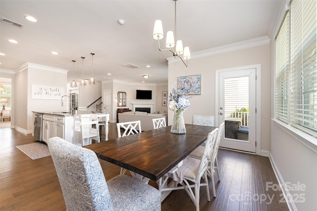 dining space featuring baseboards, crown molding, dark wood-type flooring, a fireplace, and recessed lighting
