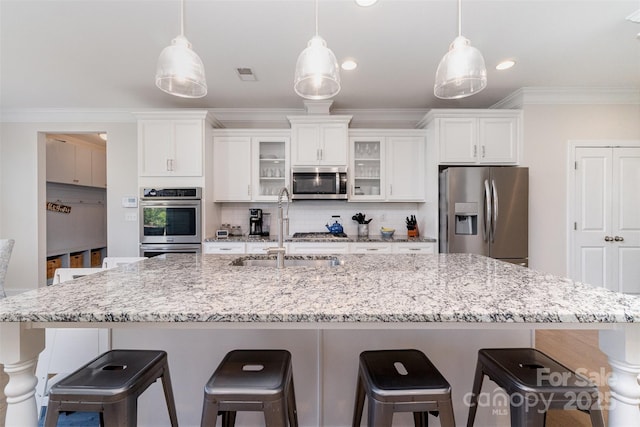 kitchen featuring appliances with stainless steel finishes, a sink, white cabinets, a large island, and crown molding