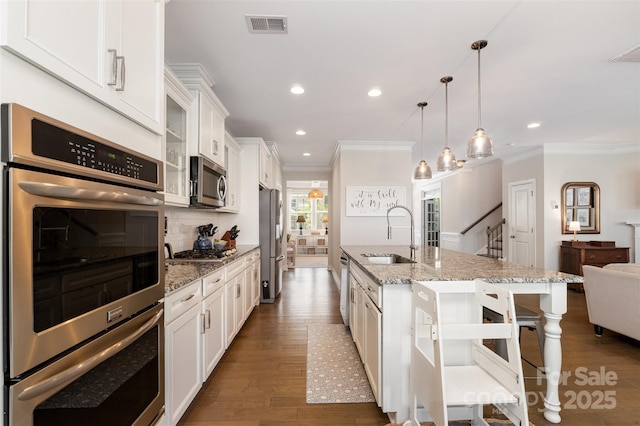 kitchen featuring a sink, appliances with stainless steel finishes, ornamental molding, a kitchen breakfast bar, and recessed lighting