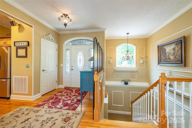 59 Carriage Highlands Ct, Hendersonville, NC 28791 - entryway with an inviting chandelier, visible vents, light wood-style flooring, and ornamental molding