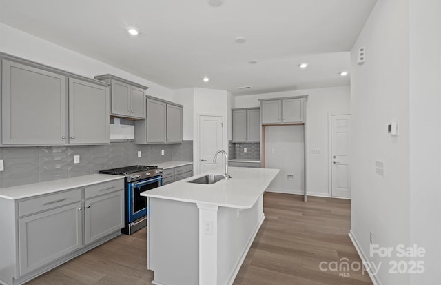 kitchen with recessed lighting, a sink, gas range, gray cabinetry, and tasteful backsplash