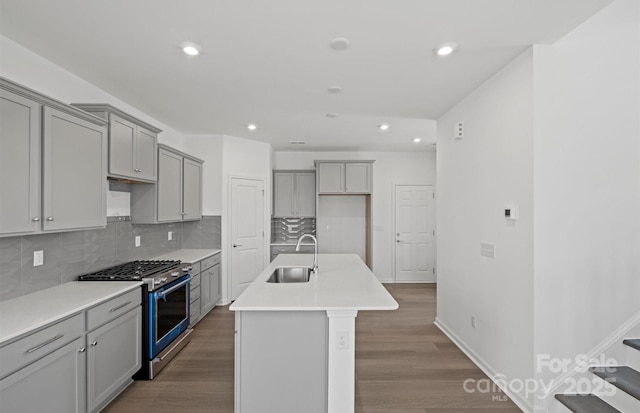 kitchen featuring recessed lighting, high end stainless steel range, backsplash, gray cabinets, and a sink