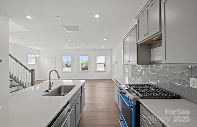 kitchen featuring gray cabinetry, appliances with stainless steel finishes, wood finished floors, and a sink
