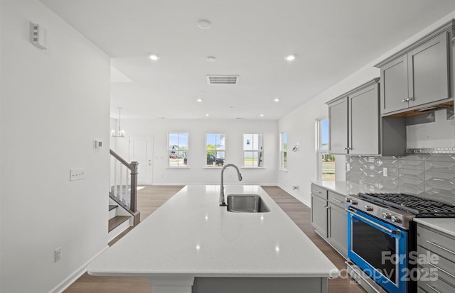 kitchen featuring gray cabinetry, visible vents, stainless steel gas stove, and a sink