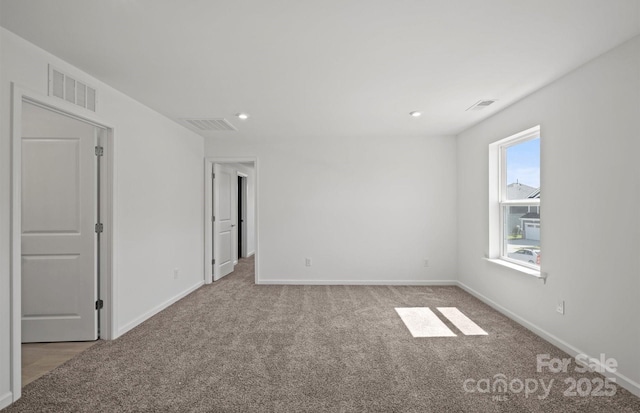 spare room with baseboards, visible vents, and light colored carpet