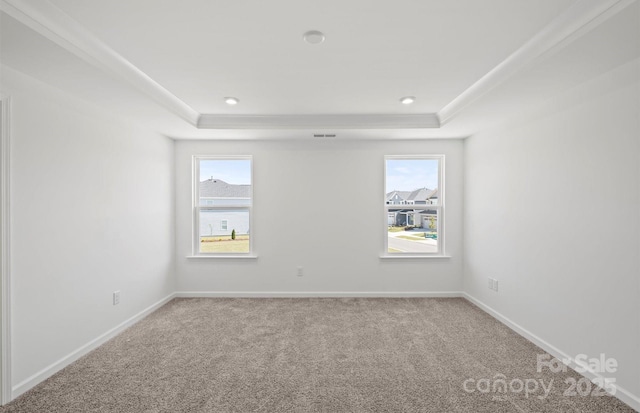 empty room featuring a tray ceiling, visible vents, carpet flooring, and baseboards