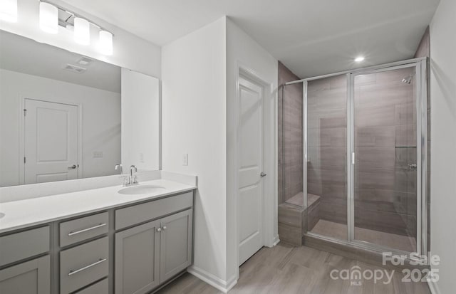 full bathroom featuring recessed lighting, double vanity, wood finished floors, a sink, and a stall shower