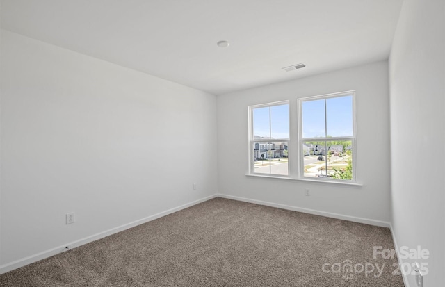 spare room featuring carpet, visible vents, and baseboards