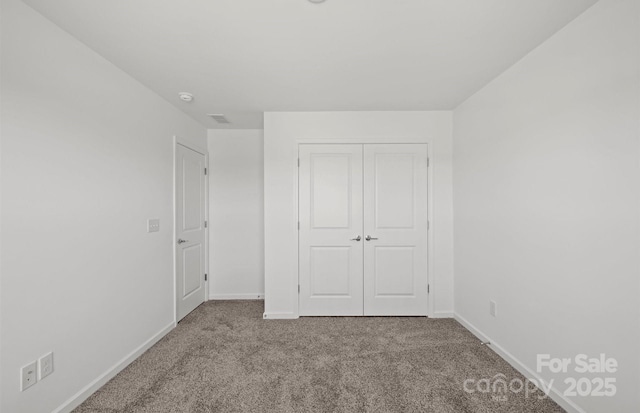 unfurnished bedroom with carpet floors, a closet, and baseboards