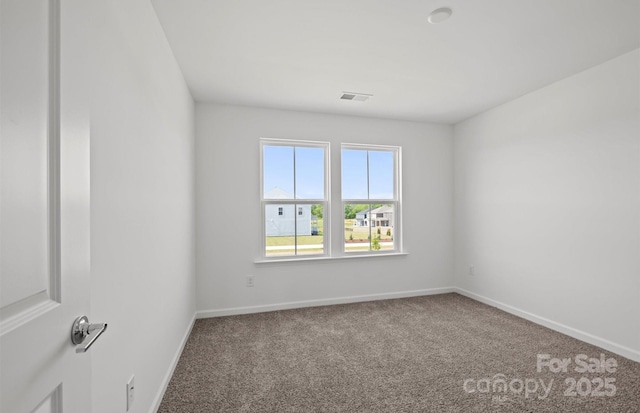spare room featuring carpet, visible vents, and baseboards