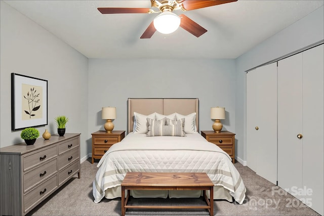 bedroom featuring light colored carpet, a ceiling fan, baseboards, and a closet