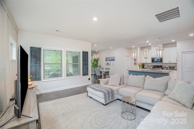 living area with recessed lighting, visible vents, a toaster, and wood finished floors