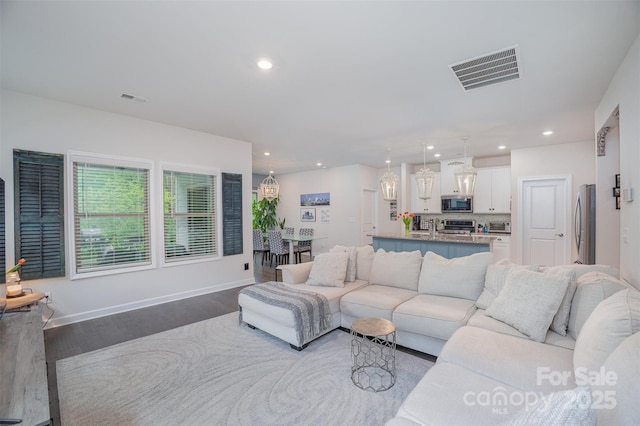 living area with wood finished floors, baseboards, visible vents, and recessed lighting