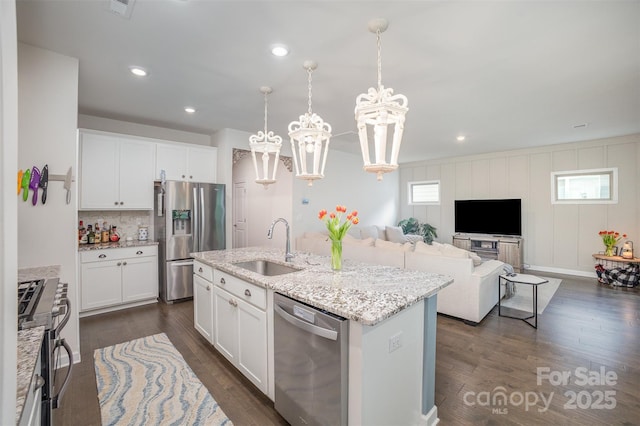 kitchen with white cabinets, a sink, stainless steel appliances, a notable chandelier, and dark wood-style floors