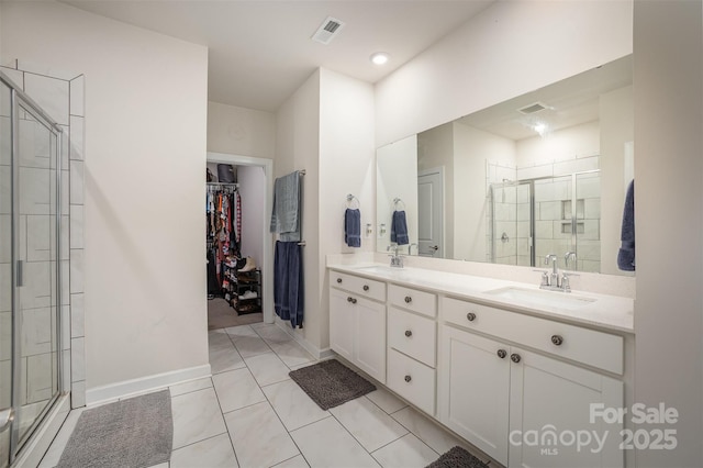 full bath featuring double vanity, a stall shower, a walk in closet, visible vents, and a sink