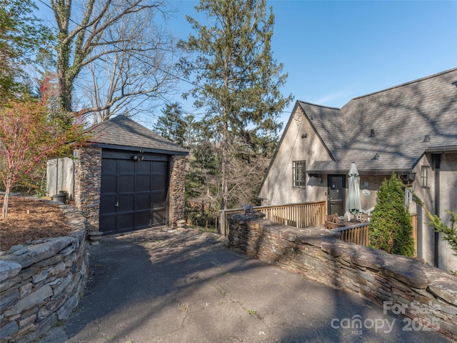 250 Kimberly Ave, Asheville, NC 28804 - view of side of home with an outbuilding, stucco siding, driveway, a detached garage, and a shingled roof
