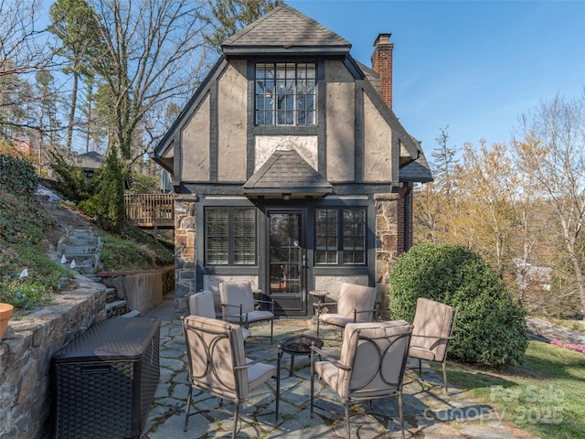 250 Kimberly Ave, Asheville, NC 28804 - rear view of property featuring stone siding, a chimney, an outdoor fire pit, a shingled roof, and a patio area