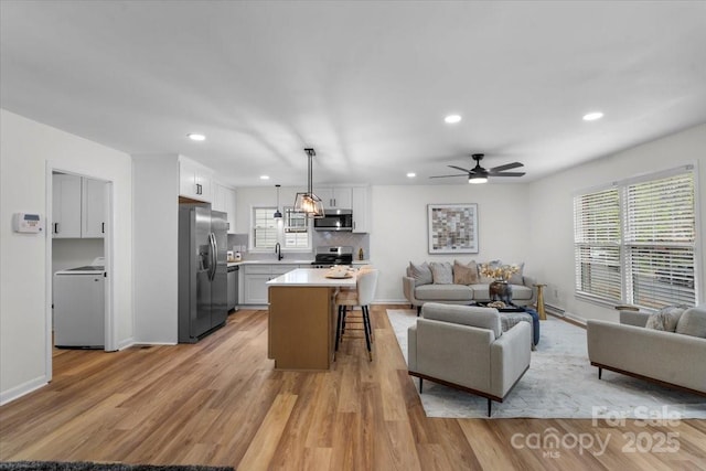 4932 Delivau Dr, Charlotte, NC 28215 - living area featuring washer / clothes dryer, light wood finished floors, ceiling fan, and recessed lighting