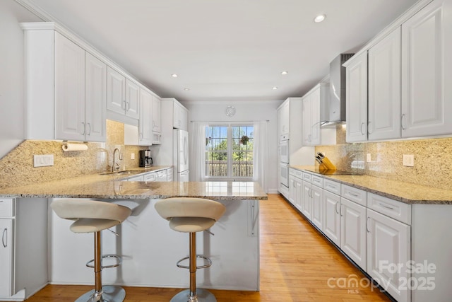 101 Skyview Dr, Asheville, NC 28804 - kitchen with wall chimney range hood, a sink, white appliances, a peninsula, and white cabinetry