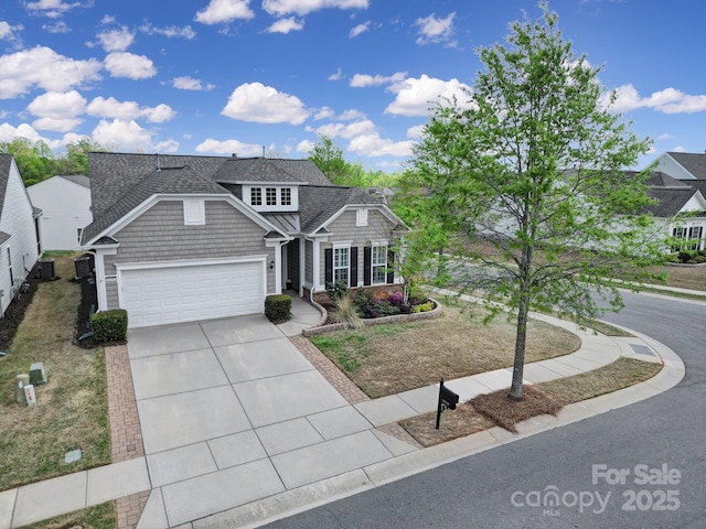 view of front of property with an attached garage, roof with shingles, and driveway
