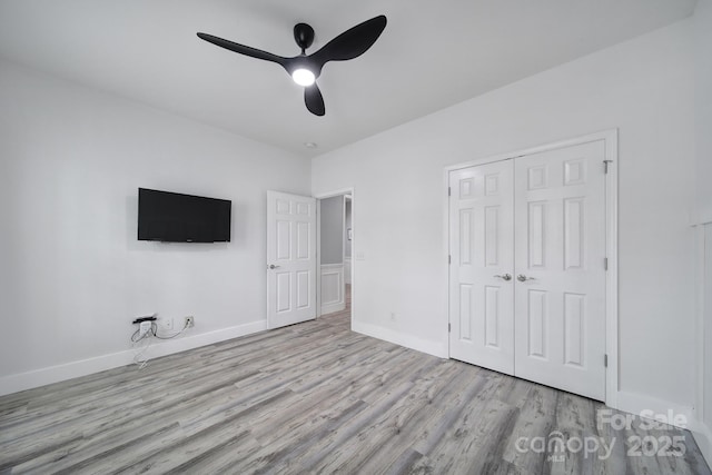 unfurnished bedroom with a closet, baseboards, ceiling fan, and wood finished floors