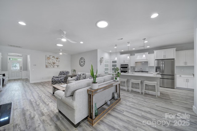 living area featuring light wood-style floors, recessed lighting, visible vents, and a ceiling fan