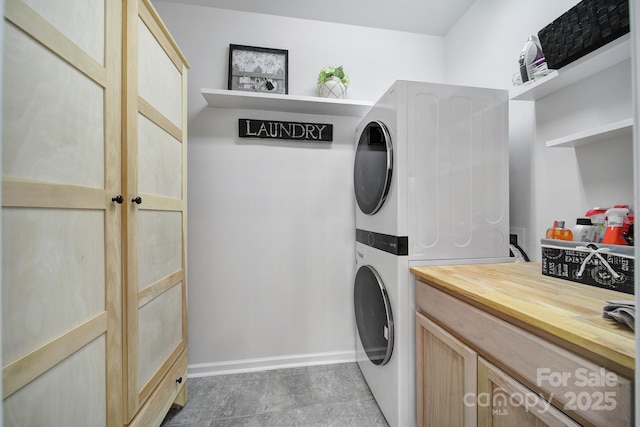 laundry area with stacked washer / dryer, laundry area, and baseboards