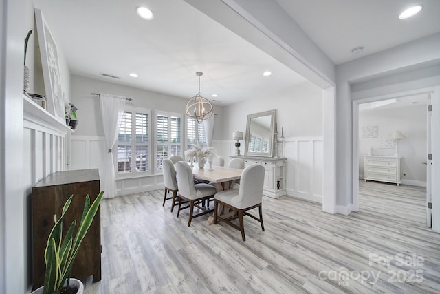 dining space with a chandelier, recessed lighting, a wainscoted wall, light wood-style floors, and visible vents