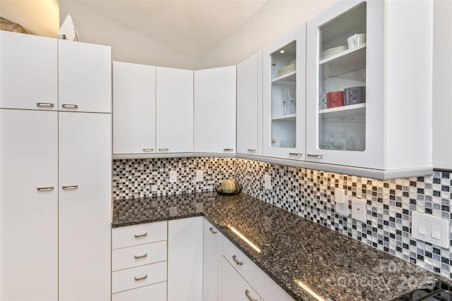 212 Chestnut Forest Rd, Fairview, NC 28730 - kitchen with tasteful backsplash, dark stone countertops, glass insert cabinets, vaulted ceiling, and white cabinets