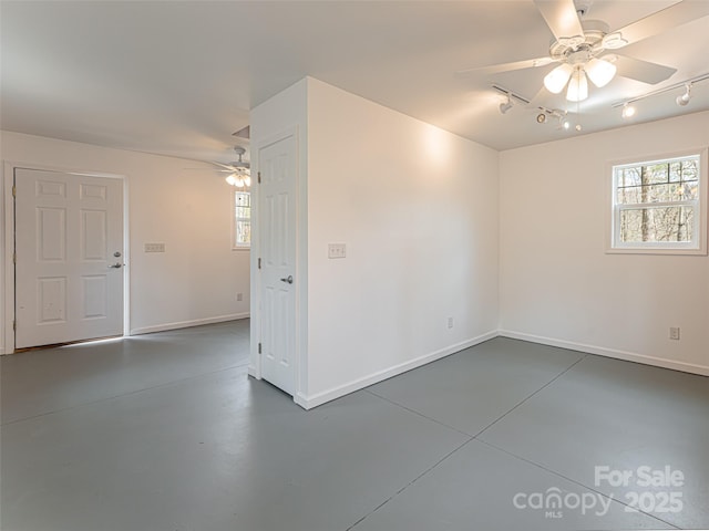 unfurnished room featuring track lighting, baseboards, finished concrete floors, and ceiling fan