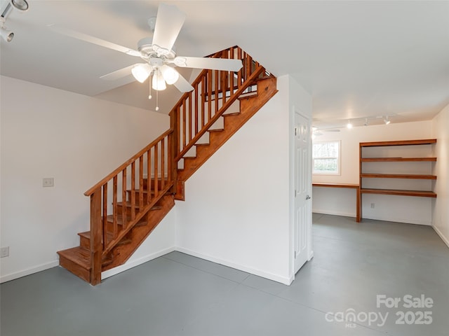 stairway with rail lighting, concrete flooring, ceiling fan, and baseboards