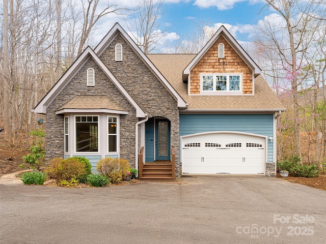 craftsman inspired home with driveway, stone siding, and a shingled roof