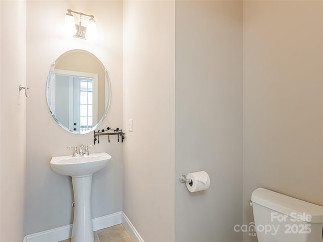 half bathroom with toilet, tile patterned floors, and baseboards
