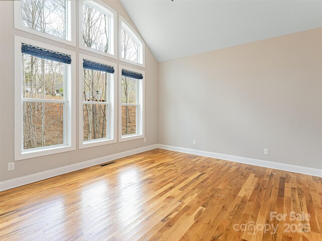 empty room with visible vents, light wood finished floors, and baseboards