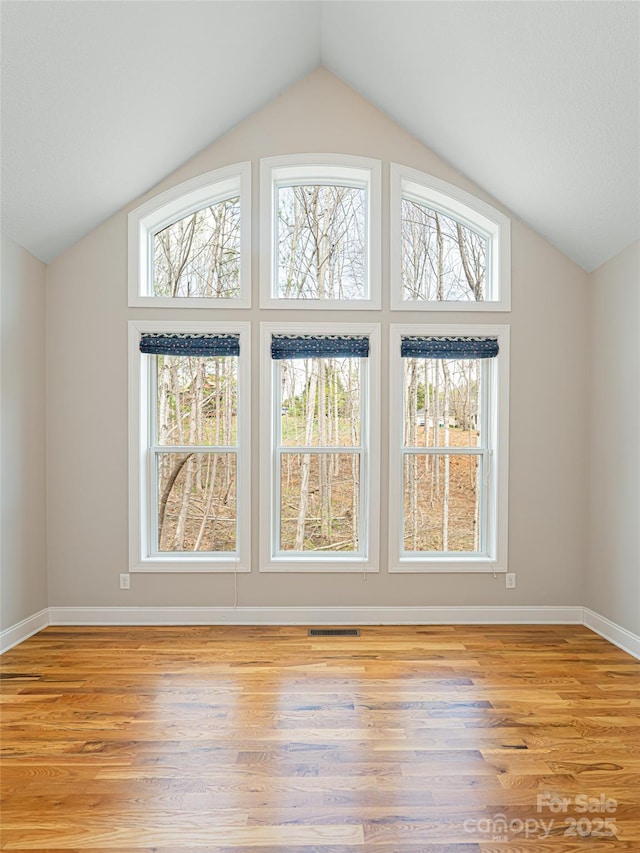 additional living space featuring visible vents, vaulted ceiling, baseboards, and light wood-style floors