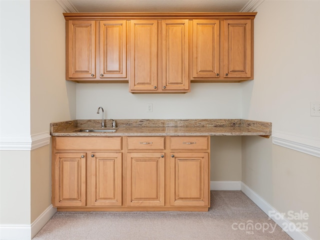 kitchen with light stone countertops, baseboards, light carpet, and a sink