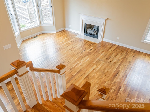 unfurnished living room with baseboards, light wood-style floors, visible vents, and plenty of natural light