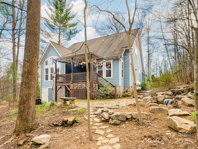 view of front of property with roof with shingles, stairs, and a deck
