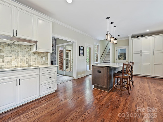 2313 Beechwood Dr, Waxhaw, NC 28173 - kitchen with stovetop, under cabinet range hood, white cabinets, decorative backsplash, and ornamental molding