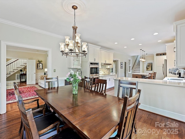 2313 Beechwood Dr, Waxhaw, NC 28173 - dining room featuring stairway, dark wood-style floors, a chandelier, ornamental molding, and recessed lighting