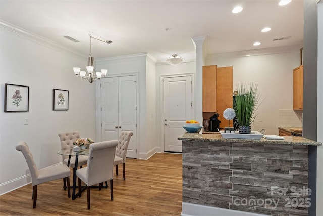 dining area with crown molding, visible vents, baseboards, light wood finished floors, and a notable chandelier