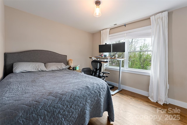bedroom with visible vents, baseboards, and wood finished floors
