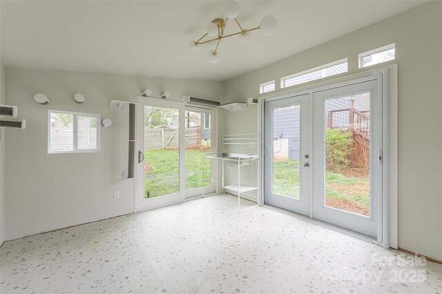 interior space featuring french doors, a wealth of natural light, and an inviting chandelier