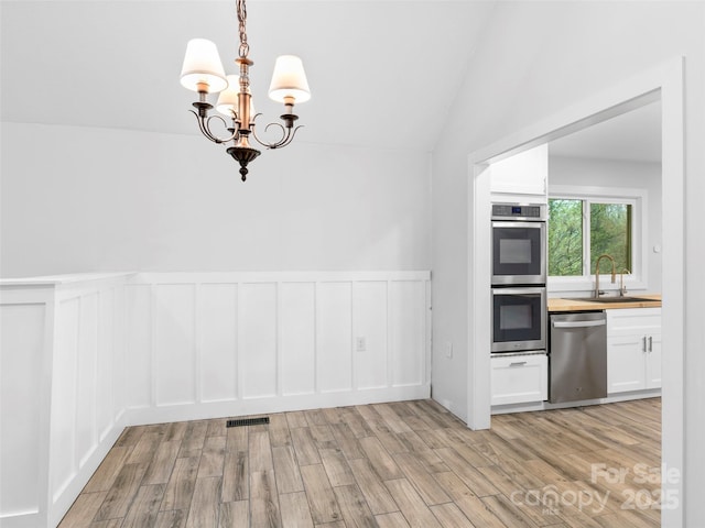 373 Vineyard Rd, Tryon, NC 28782 - unfurnished dining area featuring light wood-type flooring, a decorative wall, a sink, a chandelier, and wainscoting