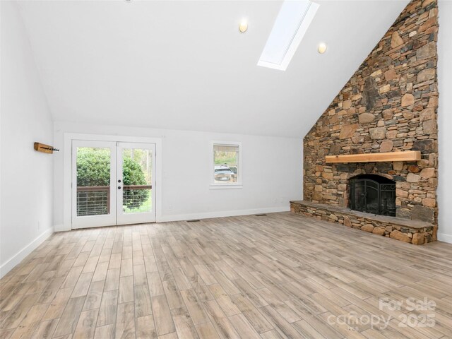 373 Vineyard Rd, Tryon, NC 28782 - unfurnished living room featuring a skylight, wood finished floors, a stone fireplace, high vaulted ceiling, and french doors